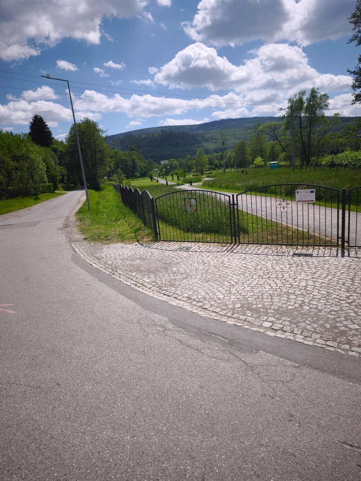 Ulica Zamkowa in Szczytna mit Einfahrtstor, im Hintergrund bewaldete Hügel