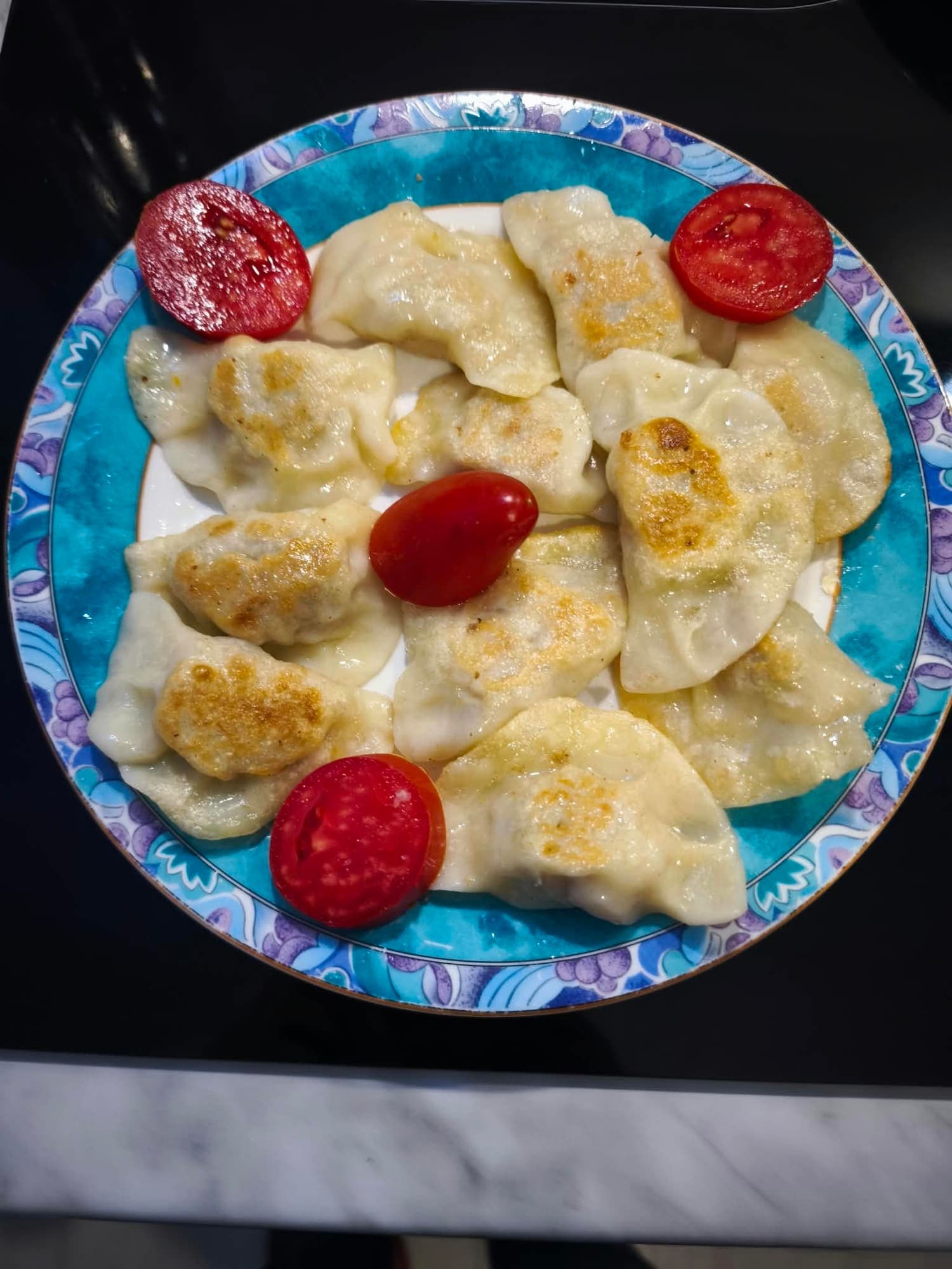 Pierogi ruskie with sour cream, served with tomatoes